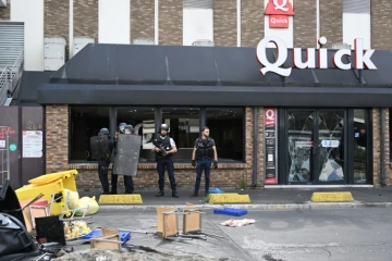 Des policiers devant un fast-food Quick aux vitres brisées pendant des émeutes, le 30 juin 2023 à Rosny-sous-Bois, en Seine-Saint-Denis