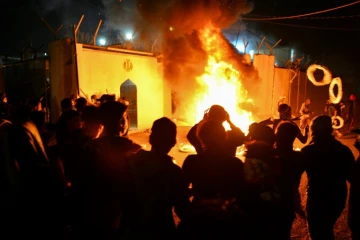 Des manifestants irakiens se rassemblent devant le consulat iranien dans la ville sainte chiite de Najaf, dans le sud de l'Irak, le 27 novembre 2019 alors que les flammes commencent à consumer le bâtiment