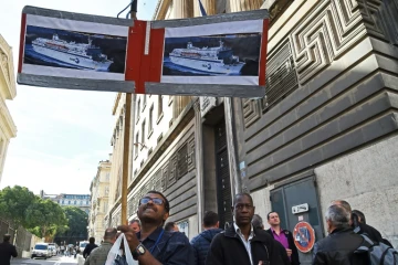 Un employé de la SNCM brandit des affiches des navires de la compagnie, le 25 septembre 2015 devant le palais de justice de Marseille 