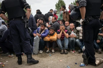 Des policiers croates devant des migrants et réfugiés qui attendent d'entrer dans le centre de transit d'Opatovac en Croatie, le 22 septembre 2015