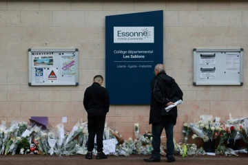 Des habitants regardent les fleurs déposées devant le collège des Sablons à Viry-Châtillon, en Essonne, le 7 avril 2024