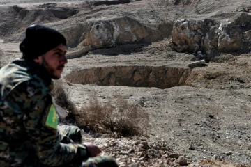 Un membre des milices paramilitaires progouvernementales du Hachd al-Chaabi assis à côté d'un gouffre connu sous le nom de Khasfa, le 26 février 2017 à Athbah, au sud de Mossoul, en Irak 