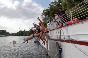 Un groupe de nageurs saute dans la Seine depuis une péniche à l'Ile-Saint-Denis, en Seine-Saint-Denis, le 2 juillet 2023