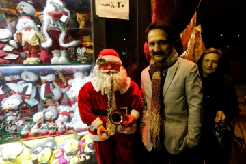 Un Iranien pose à côté d'un petit père Noël à Téhéran, le 24 décembre 2016 