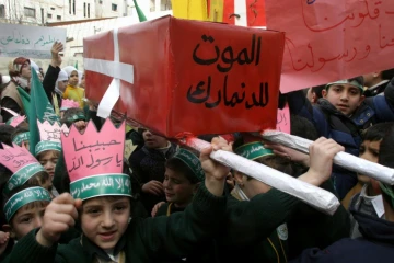 De jeunes Palestiniens défilent à Hébron, en Cisjordanie, le 13 février 2006 avec un faux cercueil ceint d'un drapeau danois sur lequel est inscrit "Mort au Danemark", en réaction à la parution en 2005 de caricatures de Mahomet dans un journal danois