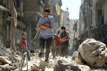 Des hommes tenant dans leurs bras des nourrissons, fuient dans un secteur tenu par les rebelles à Alep, le 11 septembre 2016, après une frappe aérienne.