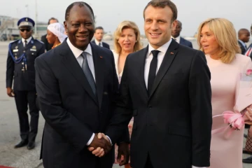 Le président français Emmanuel Macron (D) salue le président de Côte d'Ivoire Alassane Ouattara, à son arrivée à l'aéroport d'Abidjan, le 20 décembre 2019