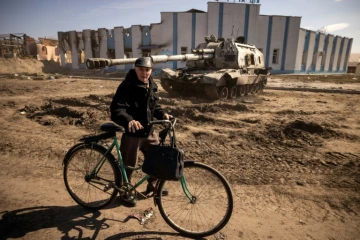 Un homme pousse sa bicyclette près d'un char endommagé à Trostyanets en Ukraine le 29 mars 2022