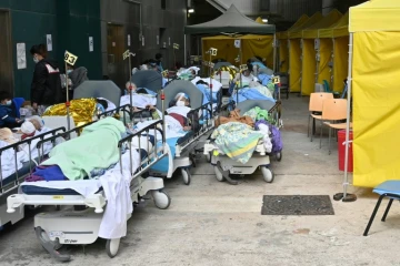 Des patients attendent sur des lits  devant le centre médical Caritas, le 15 février 2022 à Hong Kong où le nombre de contaminations au Covid-19 a grimpé en flèche