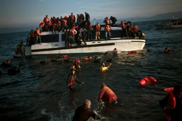 Des migrants quittent leur bateau en train de sombrer le 30 octobre 2015 sur le rivage de l'île de Lesbos en Grèce