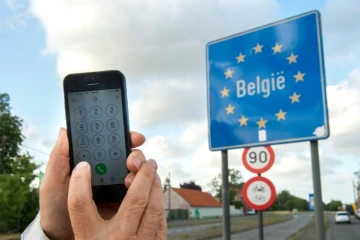 Un homme montre son téléphone portable à la frontière belge