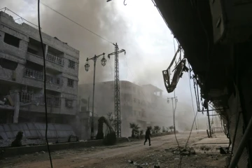 De la fumée et de la poussière s'élèvent d'une rue après des raids aériens du régime syrien sur la localité de Hammourié, dans le fief rebelle de la Ghouta orientale près de Damas, le 21 février 2018 