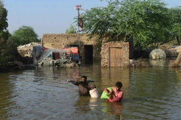 Des habitants emportent quelques biens dans une zone inondée de Shikarpur, le 31 août 2022 dans la province du Sind, au Pakistan, 