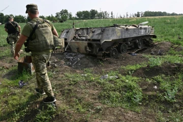 Un soldat ukrainien passe à proximité d'un char russe détruit dans un champ au sud de la ville de Mykolaiv (Ukraine) le 12 juin 2022 