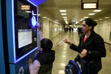 Un enfant turc et sa mère recyclent des bouteilles en plastique pour créditer leur carte de transport à Istanbul, le 9 novembre 2018