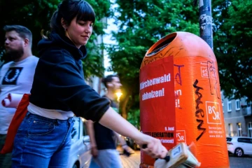 Des membres du mouvement écologiste Letzte Generation, dont la candidate Carla Hinrichs (c), collent des affiches de campagne pour les européennes, le 21 mai 2024 à Berlin 