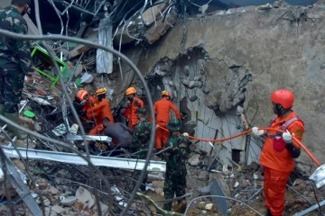 Des sauveteurs recherchent des survivants dans les ruines d'un bâtiment, à Mamuju, sur l'île des Célèbes en Indonésie, le 15 janvier 2021