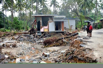 Des Indiens regardent une habitation détruite par un glissement de terrain dans le village de Kannapanakundu, dans l'Etat du Kerala (sud), le 18 août 2018