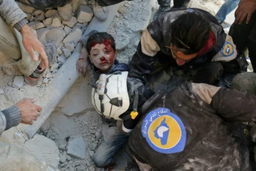 Des Casques blancs de la Défense civile syrienne sauvent un enfant des décombres d'un bâtiment détruit par un bombardement, à Bab al-Nairab, dans le nord d'Alep, le 24 novembre 2016