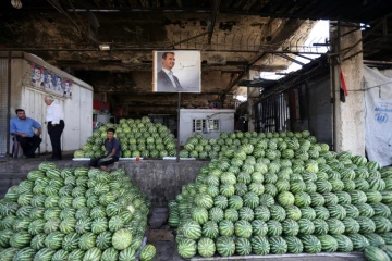 Des négociants syriens près du portrait du président Bachar al-Assad au marché des Halles de Damas, le 21 septembre 2015