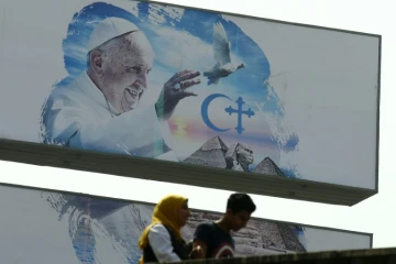 Des passants devant une affiche annonçant la visite papale, le 27 avril 2017 au Caire 