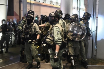 Des policiers sortent du centre commercial Langham Place après y avoir cherché des manifestants, le 26 déceùbre 2019 dans le quartier de Mong Kok, à Hong Kong