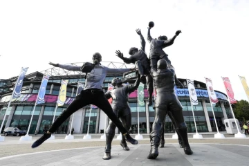 Un homme devant les statues de joueurs de rugby devant le stade Twickenham le 17 septembre 2015 à Londres 