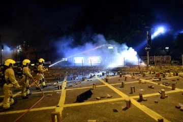 Des pompiers interviennent pour éteindre le feu sur des barricades bloquant une route près de l'université polytechnique de Hong Kong 