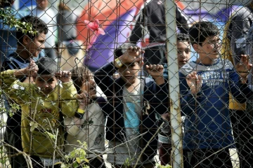 Des enfants se tiennent derrière le grillage entourant le camp de migrants de Moria transformé en camp de détention, à Mytilène, sur l'île grecque de Lesbos, le 3 avril 2016