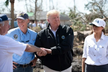 Le président américain Donald Trump (au centre), avec sa femme Melania à ses côtés et le gouverneur de Floride Rick Scott (à gauche) constatent les dégâts après le passage de l'ouragan Michael, à Lynn Haven, le 15 octobre 2018