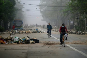 Des cyclistes passent des barricades érigées par les protestataires, à Rangoun le 11 mars 2021