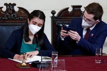 La présidente de la Convention constituante, Maria Elisa Quinteros (g), signe la dernière version de la nouvelle Constitution qui sera soumise à référendum, photographiée par son vice-président, Gaspar Dominguez, le 4 juillet 2022 à Santiago