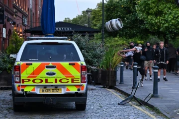 Un manifestant jette un fût de bière sur une voiture de police, à Bristol, le 3 août 2024