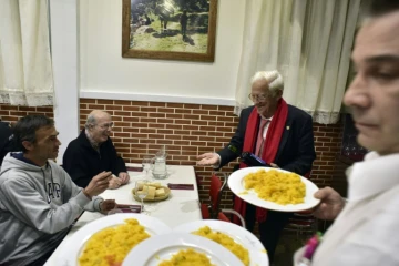 Le prêtre Angel Garcia (à droite) en compagnie de sans-abris pendant leur dîner au restaurant "Robin des Bois" de Madrid, le 1er décembre 2016