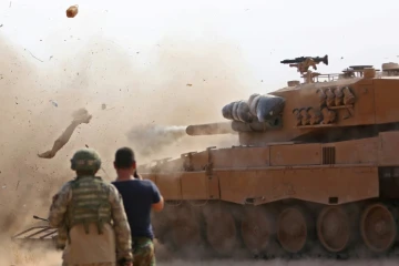 Des soldats turcs observent un char de leur armée tirer sur des positions d'une milice kurde, à Ras al-Aïn (nord de la Syrie), le 28 octobre 2019
