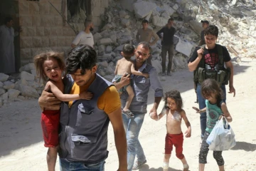 Des Syriens éloignent des enfants d'un quartier d'Alep (Syrie), tenu par des rebelles au régime d'Assad et qui a été la cible de bombardements aériens le 25 juillet 2016 