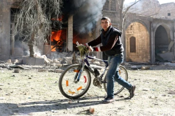 Un jeune syrien pousse son vélo après une frappe aérienne sur un quartier rebelle d'Alep, le 19 novembre 2016 
