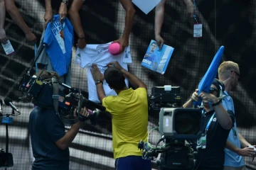 Novak Djokovic signe des autographes après sa victoire face au jeune sud-coréen Chung Hyeon à l'Open d'Australie, le 18 janvier 2016 à Melbourne