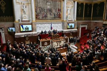 Députés et sénateurs français applaudissent lors d'une visioconférence avec le président ukrainien Volodymyr Zelensky à l'Assemblée nationale à Paris, le 23 mars 2022