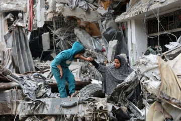 Une enfant joue au côté d'une Palestinienne dans les ruines d'un bâtiments détruit par un bombardement israélien, le 8 avril 2024 dans la ville de Gaza