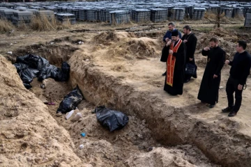 Des prêtres prient devant une fosse commune avec de nouveaux cadavres, dans la petite ville ukrainienne de Boutcha, le 7 avril 2022