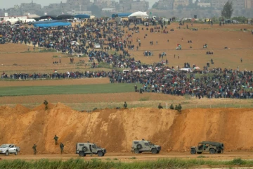 Une photo prise le 30 mars 2018 du côté israélien de la frontière, montre des Palestiniens participant à des manifestations dans la bande de Gaza, sous le regard des militaires israéliens