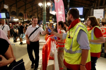 Des membres de la Croix Rouge distribuent de l'eau aux voyageurs coincés dans la soirée à la Gare du Nord, le 19 juillet 2016 à Paris