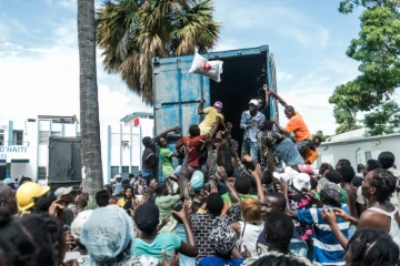 Un homme lance un sac de riz dans la foule aux Cayes, ville ravagée par le séisme, le 20 août 2021