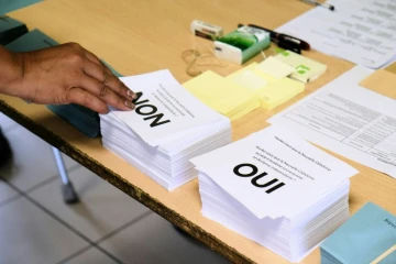 Une personne prend les bulletins avant de voter au référendum sur l'indépendance de la Nouvelle-Calédonie, le 4 octobre 2020 dans un bureau à Nouméa