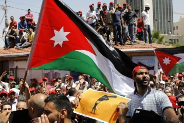 Des Jordaniens brandissent le drapeau national et scandent des slogans contre l'austérité, le 6 juin 2018 à Amman