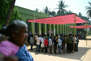 Des électeurs, à l'abri du soleil sous un auvent, attendent pour voter, le 26 avril 2024 à Bangalore, en Inde