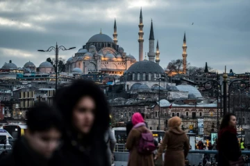Des piétons traversent le pont de Galata à Istanbul, le 27 janvier 2018, avec la mosquée de Suleymaniye en arrière-plan