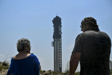 Des personnes observent la fusée Starship sur la rampe de lancement avant son quatrième vol d'essai à la base spatiale Starbase de SpaceX à Boca Chica, au Texas, le 5 juin 2024