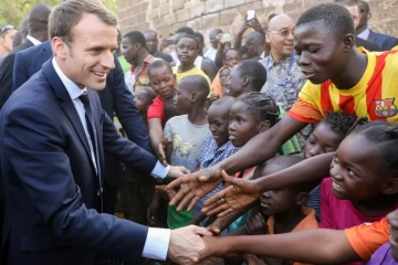 Emmanuel Macron serrant les mains d'enfants burkinabés, après la visite d'une école de Ouagadougou, le 28 novembre 2017